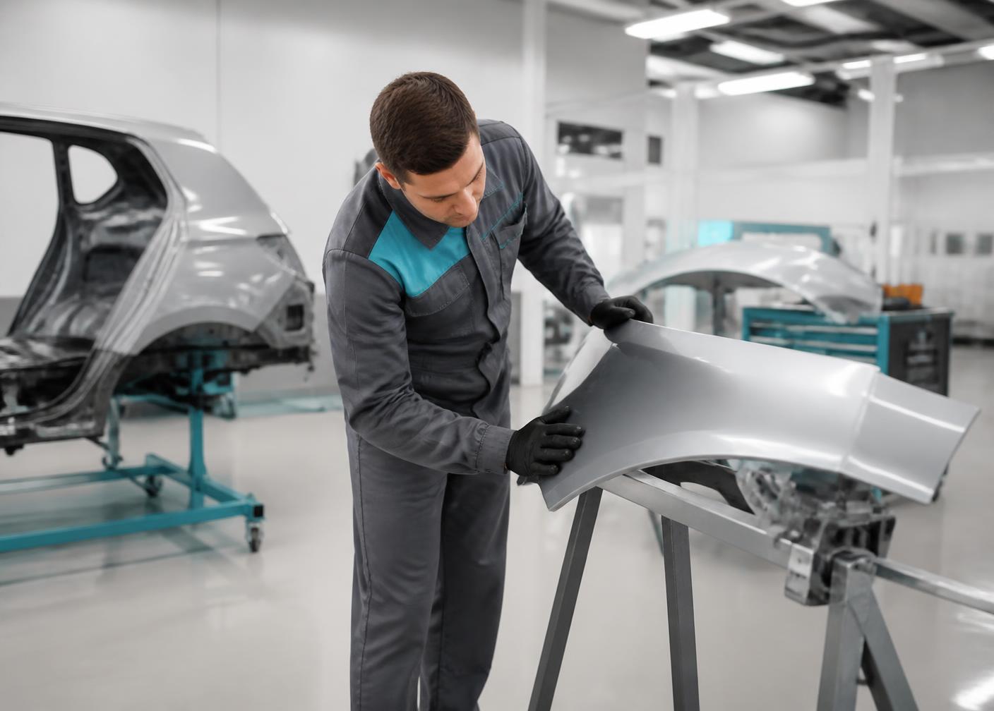 Technician inspecting a repaired panel in a modern smash repair workshop